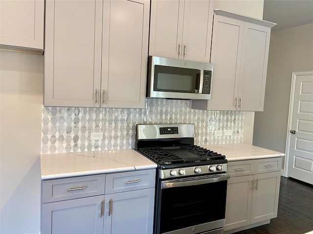 kitchen featuring backsplash, stainless steel appliances, light stone counters, and white cabinetry