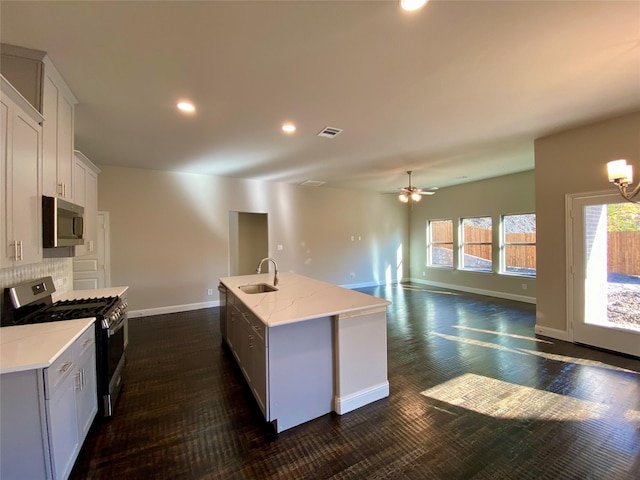 kitchen featuring backsplash, stainless steel appliances, sink, white cabinets, and an island with sink