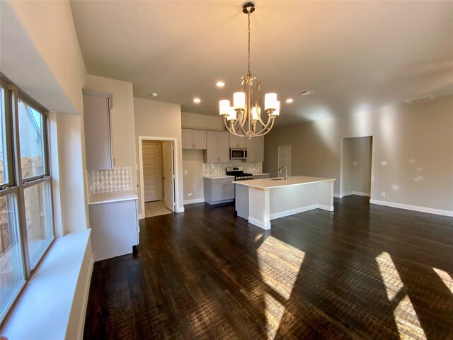 kitchen featuring a center island with sink, appliances with stainless steel finishes, a sink, light countertops, and backsplash