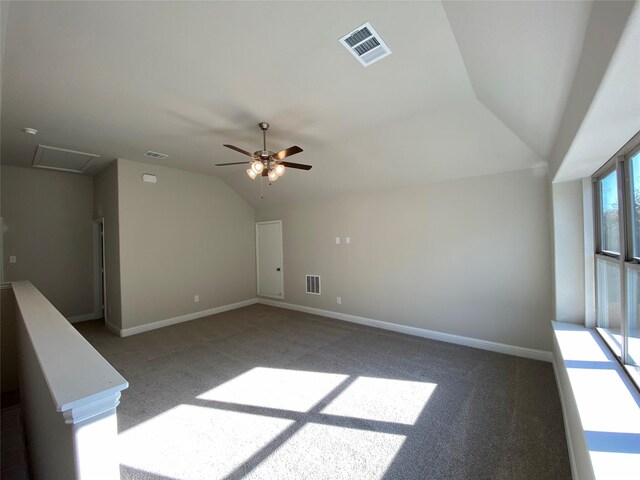 carpeted empty room featuring baseboards, visible vents, and vaulted ceiling