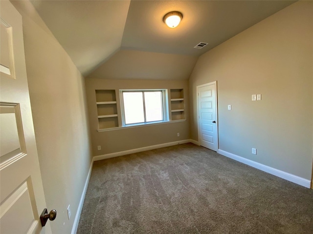 empty room featuring carpet, built in shelves, and lofted ceiling