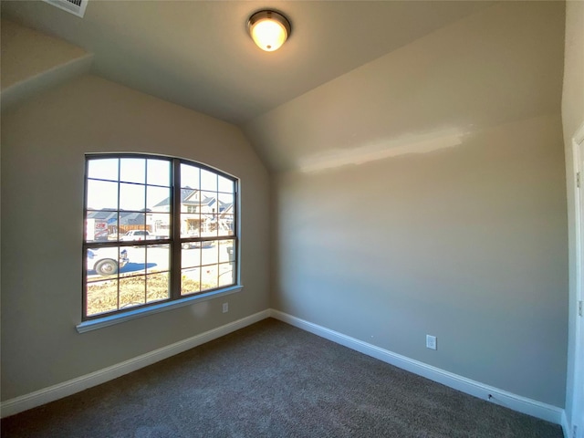 empty room featuring dark carpet and vaulted ceiling