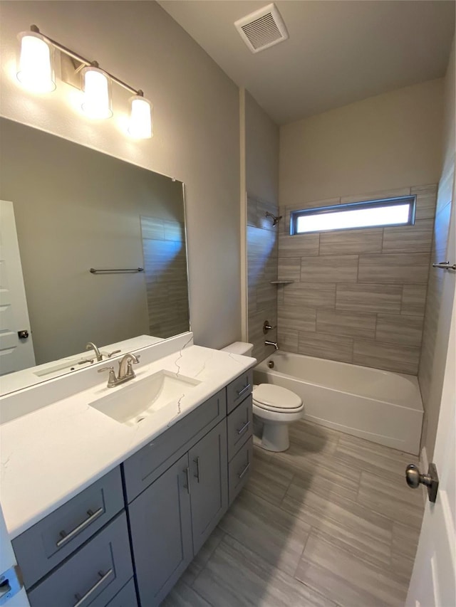 full bathroom featuring tiled shower / bath combo, toilet, and vanity