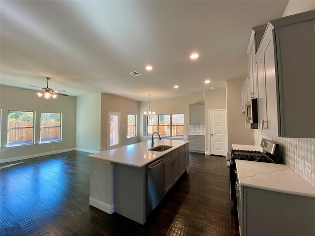 kitchen featuring a center island with sink, sink, tasteful backsplash, dark hardwood / wood-style flooring, and stainless steel appliances