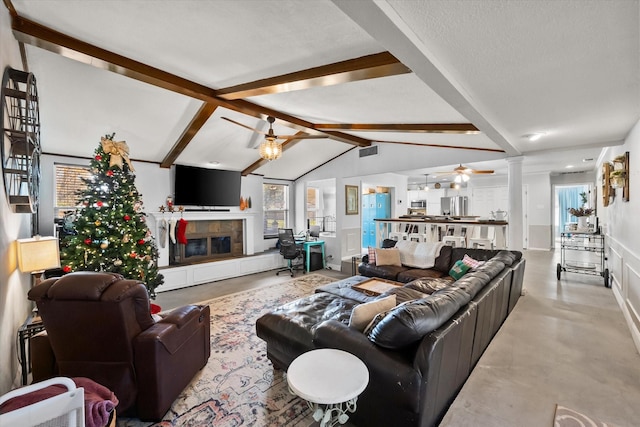 living room with a tiled fireplace, lofted ceiling with beams, decorative columns, and ceiling fan