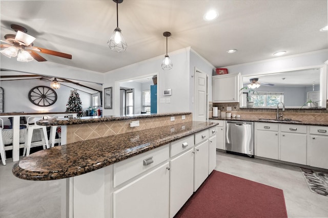 kitchen featuring decorative backsplash, stainless steel dishwasher, sink, pendant lighting, and white cabinets