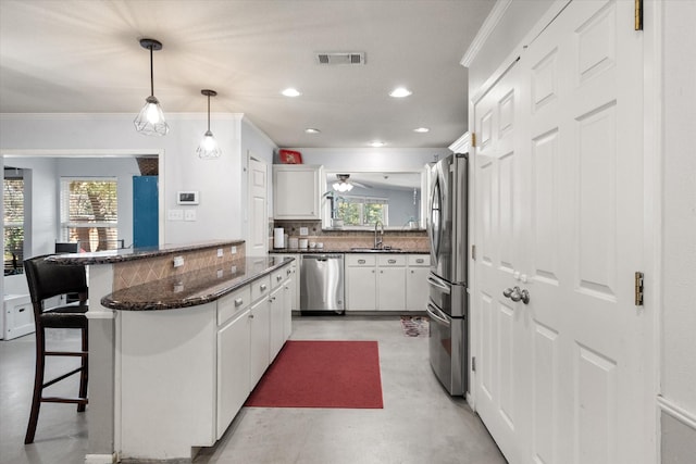 kitchen with backsplash, white cabinets, a kitchen breakfast bar, sink, and stainless steel appliances