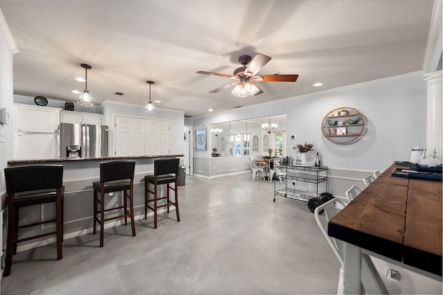 interior space with dark stone counters, ceiling fan, stainless steel fridge, decorative light fixtures, and white cabinetry