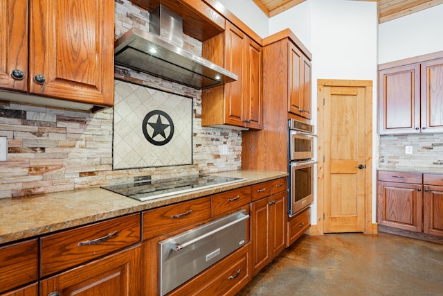 kitchen with light stone countertops, black electric stovetop, stainless steel double oven, wall chimney range hood, and backsplash