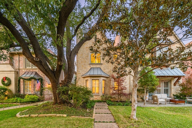 tudor-style house featuring a front lawn and a patio area