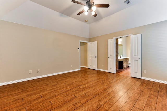 unfurnished bedroom featuring hardwood / wood-style flooring, ceiling fan, lofted ceiling, and ensuite bathroom