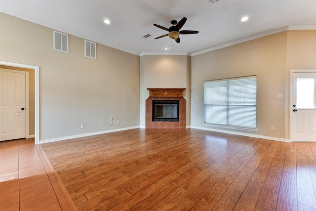 unfurnished living room featuring crown molding, ceiling fan, a tile fireplace, and light hardwood / wood-style flooring