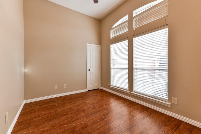 empty room with a high ceiling, dark hardwood / wood-style floors, and ceiling fan