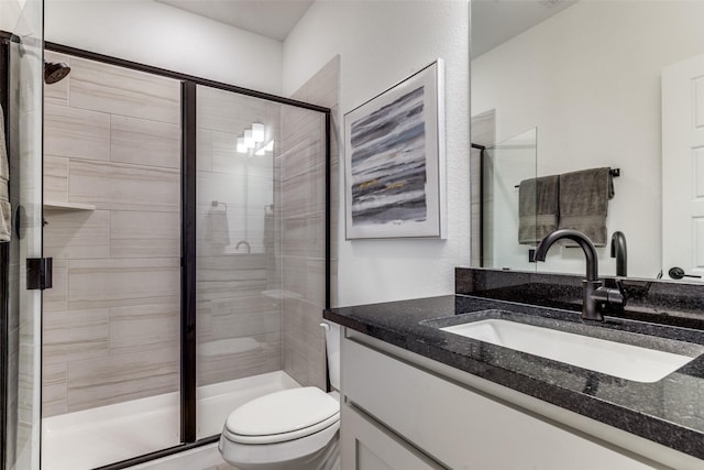 bathroom featuring vanity, toilet, and a shower with door