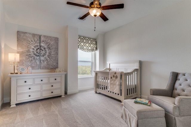 bedroom featuring ceiling fan, light carpet, and a nursery area