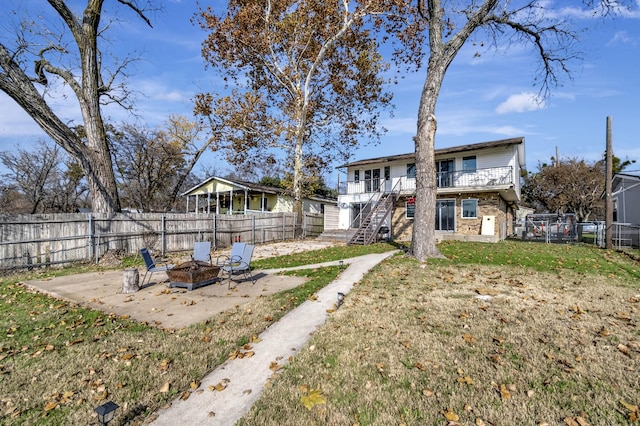 view of yard featuring a patio area, a balcony, and an outdoor fire pit