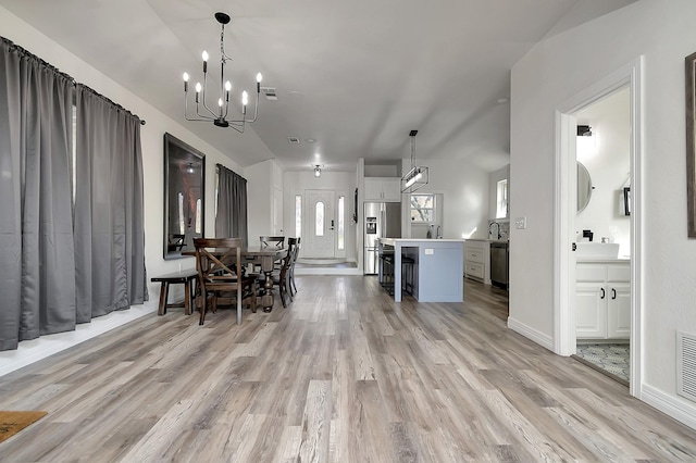 dining space with light hardwood / wood-style floors, lofted ceiling, a wealth of natural light, and a chandelier