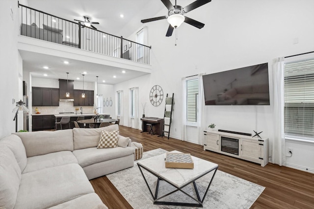 living room with ceiling fan, dark hardwood / wood-style flooring, and a towering ceiling