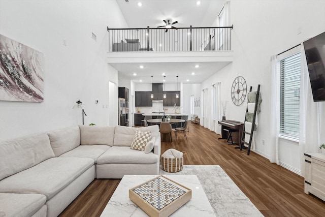 living room featuring ceiling fan, dark hardwood / wood-style flooring, and a high ceiling