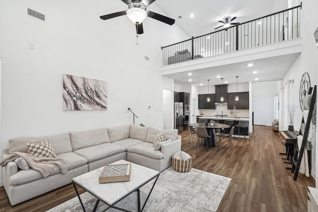 living room with a towering ceiling, dark hardwood / wood-style floors, ceiling fan, and sink