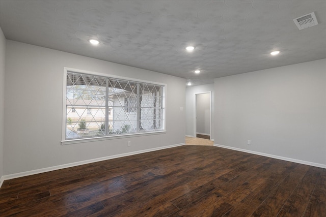 unfurnished room with dark hardwood / wood-style flooring and a textured ceiling