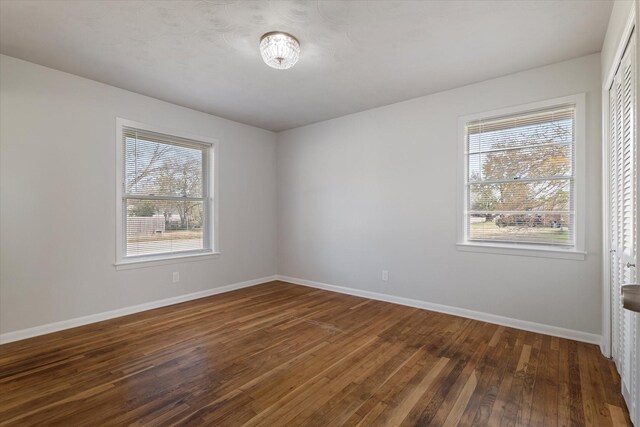 empty room with dark wood-type flooring and a healthy amount of sunlight