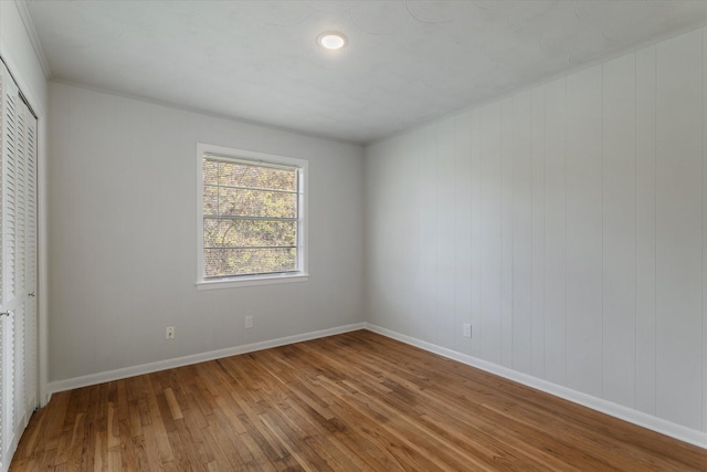 unfurnished bedroom featuring a closet, hardwood / wood-style floors, and wooden walls