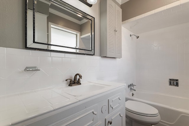 full bathroom featuring tiled shower / bath, vanity, toilet, and tile walls