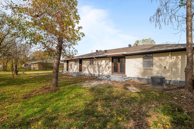 back of house with central AC unit and a yard