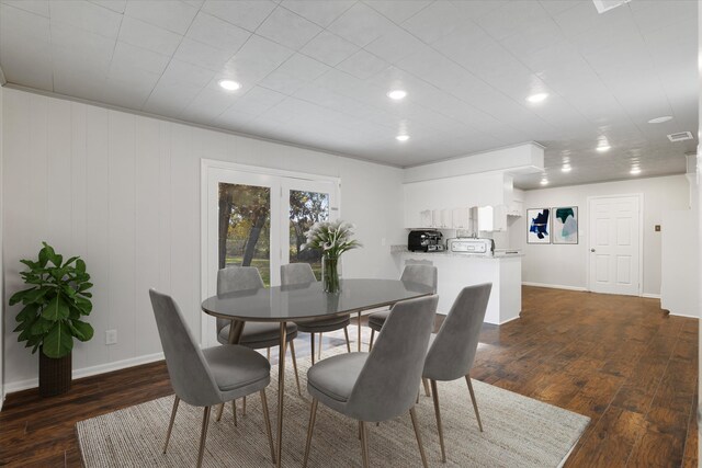 dining space featuring wood walls, dark hardwood / wood-style floors, and ornamental molding