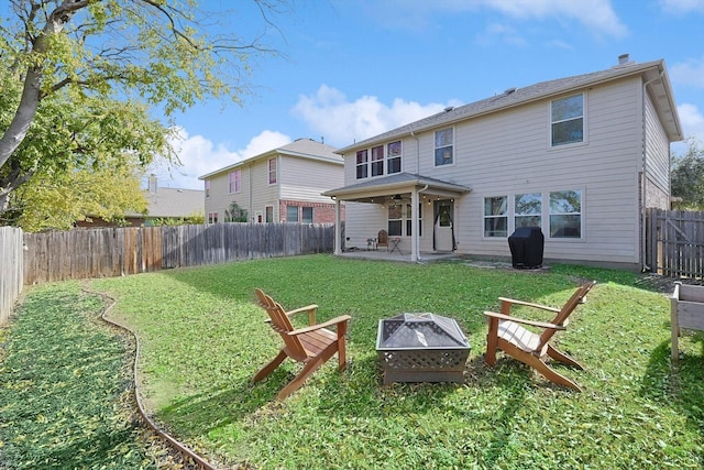 back of property with a yard, a patio area, and a fire pit