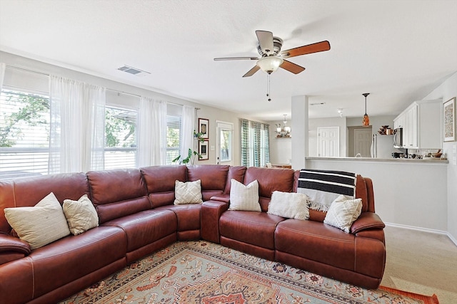 living room featuring ceiling fan with notable chandelier and light carpet