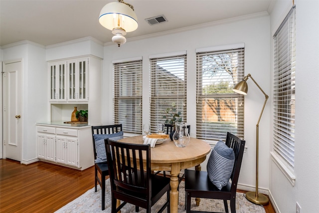 dining area with ornamental molding and hardwood / wood-style flooring