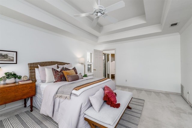 bedroom featuring ceiling fan, ornamental molding, light carpet, and a tray ceiling