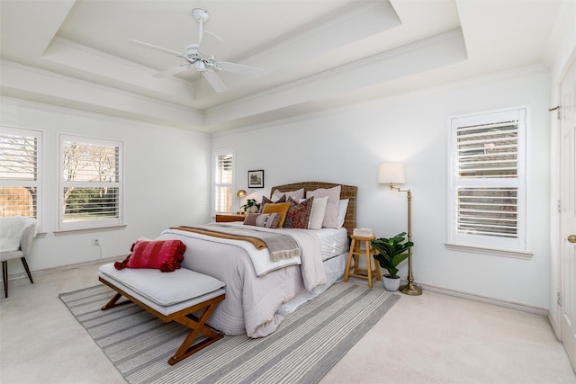 carpeted bedroom with ceiling fan, a tray ceiling, and ornamental molding