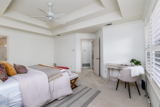 bedroom featuring ensuite bathroom, ceiling fan, a tray ceiling, ornamental molding, and light carpet