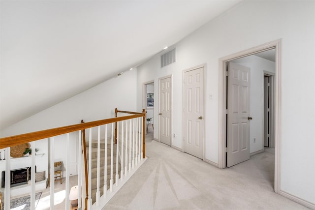 hall featuring light colored carpet and lofted ceiling