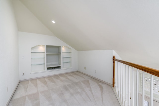 additional living space with vaulted ceiling, light carpet, and built in shelves