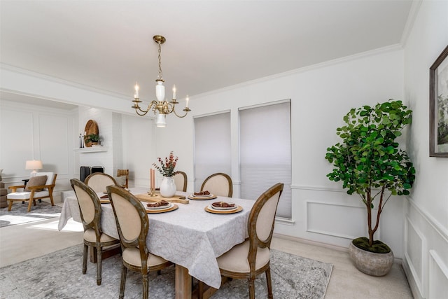 dining room featuring a large fireplace, light colored carpet, ornamental molding, and a chandelier