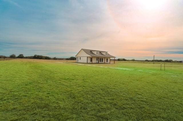 yard at dusk featuring a rural view