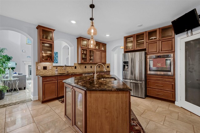 kitchen with sink, decorative backsplash, dark stone countertops, decorative light fixtures, and stainless steel appliances