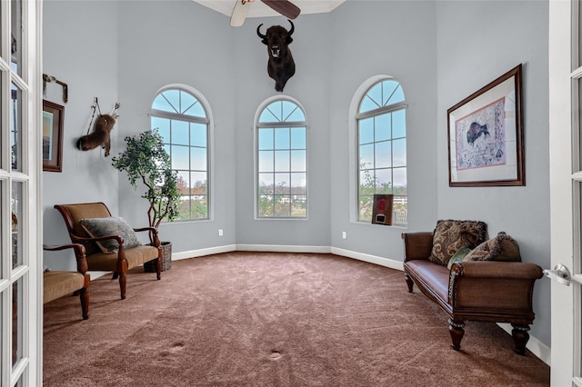 living area with ceiling fan, carpet floors, a towering ceiling, and french doors