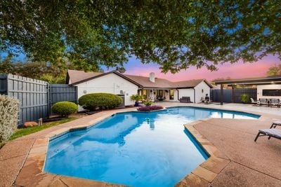 pool at dusk featuring a fenced backyard, a fenced in pool, and a patio