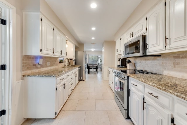 kitchen with light stone countertops, stainless steel appliances, white cabinets, and light tile patterned flooring