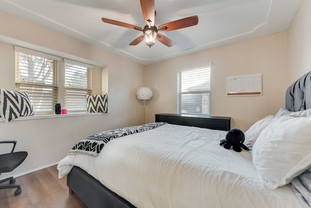 bedroom featuring ceiling fan, wood-type flooring, and multiple windows