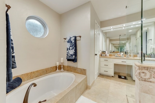 bathroom with tile patterned flooring, vanity, and a relaxing tiled tub