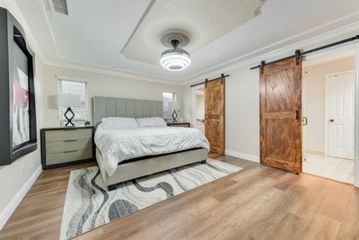 bedroom with hardwood / wood-style flooring, a barn door, and crown molding