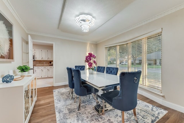 dining room featuring light hardwood / wood-style flooring, ornamental molding, and a textured ceiling