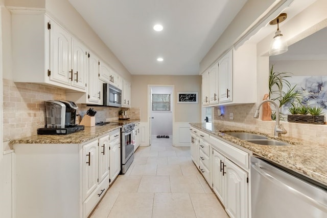 kitchen featuring white cabinetry, stainless steel appliances, light stone countertops, and sink