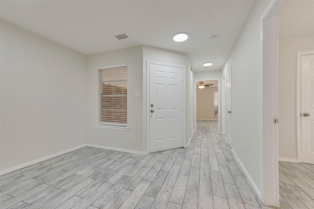 hall featuring a textured ceiling and light hardwood / wood-style floors